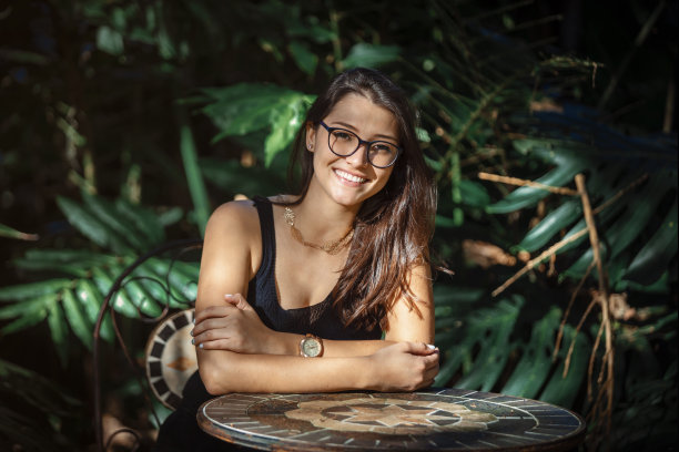 美丽年轻的拉丁妇女坐在一张桌子与丛林类型的背景图片下载