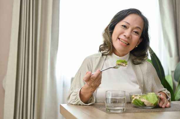 迷人的亚洲年龄的妇女喜欢吃健康的沙拉在她舒适的餐厅图片下载