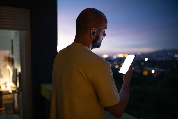 男子商人在黄昏时在家中阳台上使用手机图片下载