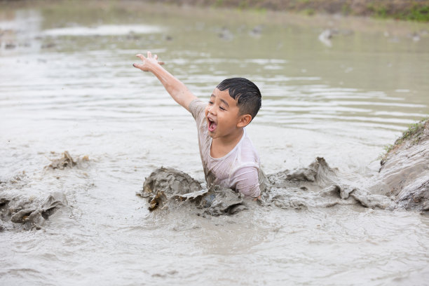 夏天的一天，快乐的小男孩在又大又湿的泥土里玩耍图片下载