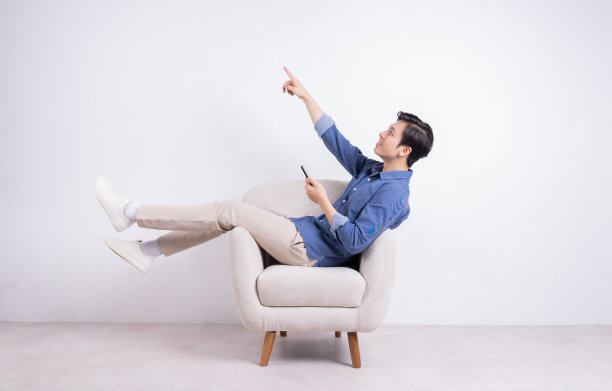 年轻的亚洲男子坐在白色背景的扶手椅上图片下载