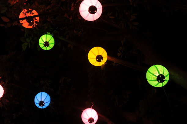 夜晚挂在树上的彩色纸灯笼，在黑暗中发光图片下载
