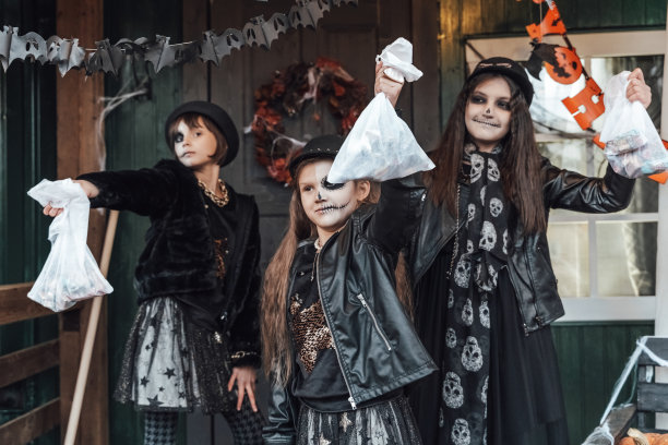 可怕的爱的家庭夫妻男人，女人庆祝万圣节。可怕的黑色骷髅半脸妆，女巫服装，纹身，时髦的形象，夹克，帽子。恐怖，有趣的摄影，节日派对。玄关的装饰。家里，户外，街上的南瓜南瓜灯图片下载