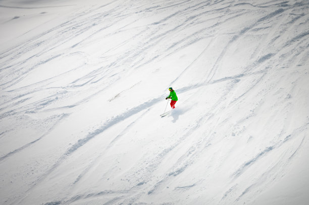 俯视图，滑雪者从雪道外的斜坡上滑下，身后留下一条小道图片下载