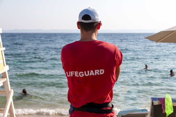 海滩上一个年轻的男性救生员的背影。暑假图片下载