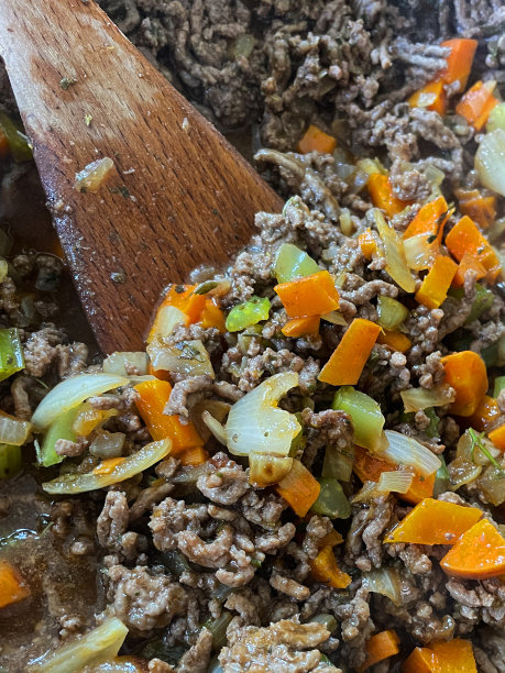 全画幅图片，煎锅里的肉末，切碎的芹菜，洋葱丁和胡萝卜作为肉酱汁或牧羊人派的基础，用木铲搅拌，高架视图图片下载