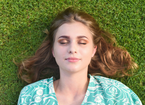 美丽的白俄罗斯妇女睡觉，躺在草地上闭着眼睛图片下载