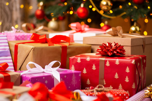 用彩色包装纸包装的圣诞礼物放在圣诞树下的地板上图片下载