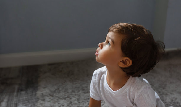 一个小孩抬头望着阳光。图片下载