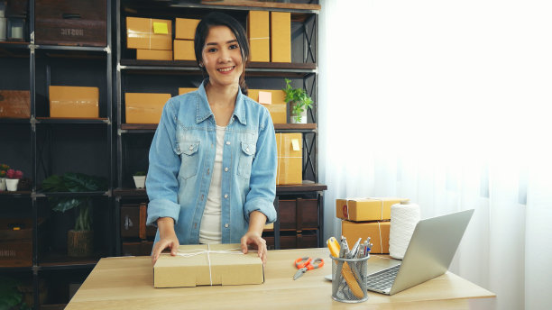 妇女包装盒子在桌子上检查货物包装交付发货给客户。亚洲女性在家里的办公桌上创业。企业家亚洲妇女包装产品的快递项目图片下载