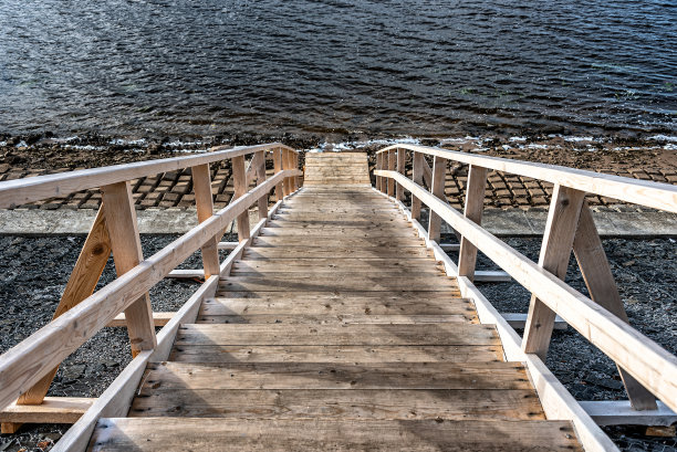 有栏杆的木制楼梯通向水边。图片下载