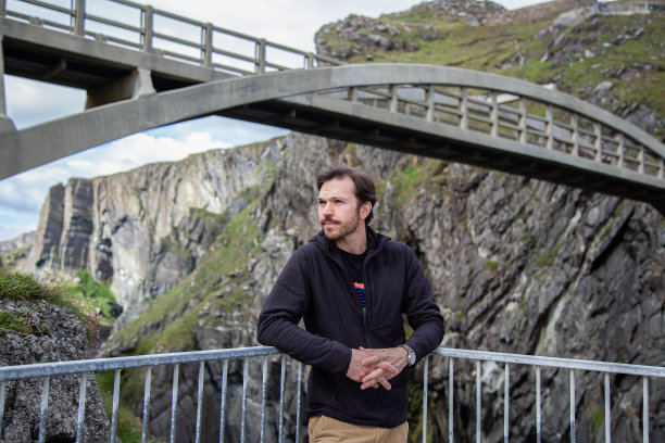 爱尔兰米森海德大桥上，一名白人男子倚在栏杆上向前看。体贴的男人图片下载