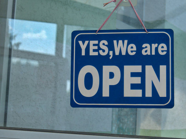 商店玻璃门上挂着“Yes, We are OPEN”的牌子图片下载