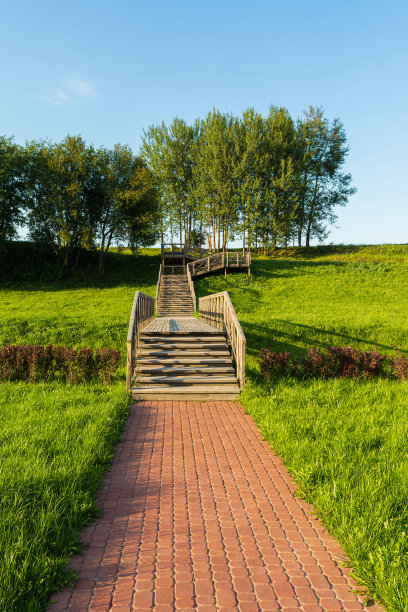 在一个风景如画的地方，一个有田野和树木的多层次木制舷梯的视图。夏夜日落前。自然环境背景图片下载