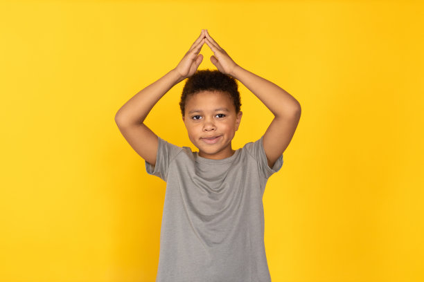 快乐的前十岁男孩在头顶做屋顶手势的肖像图片下载