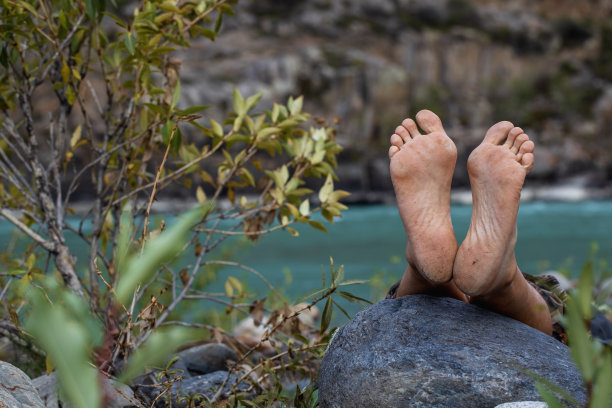 夏天没穿鞋的脚踩在石头上。男性旅行者，鞋跟粗糙，有裂缝。图片下载