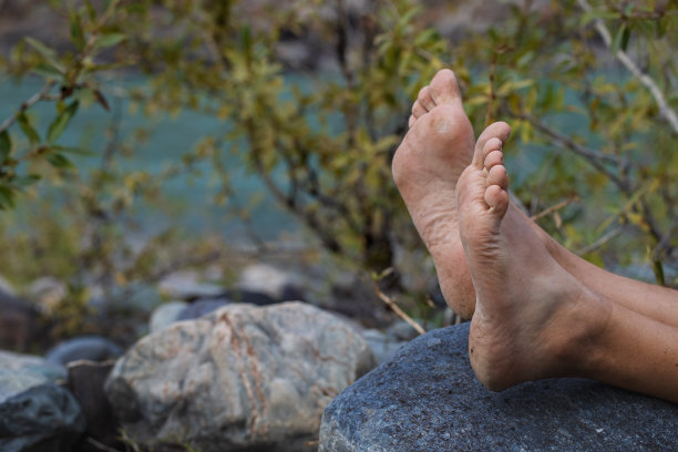 夏天没穿鞋的脚踩在石头上。男性旅行者，鞋跟粗糙，有裂缝。图片下载
