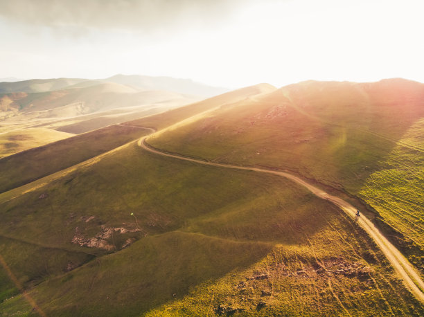 航拍自行车在风景秀丽的亚美尼亚乡村山区自行车旅行户外独自在温暖的夏季景观与明亮的天空背景日落。鼓舞人心的自行车图片图片下载