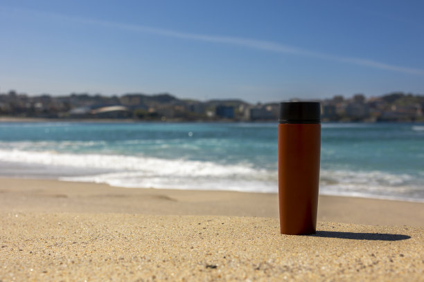 海边沙滩上的红色热杯。图片下载