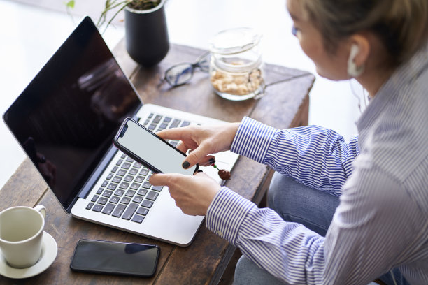 成熟的亚洲女性在家使用手机和笔记本电脑工作图片下载