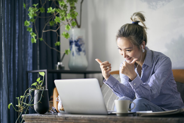 成熟的亚洲女性在家工作，用笔记本电脑视频聊天图片下载