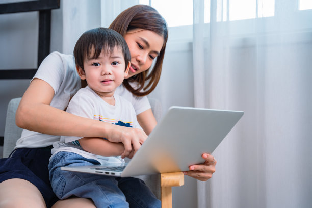 妈妈她正在打开电脑上的东西给她可爱的小儿子看。图片下载