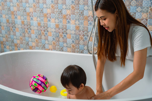 妈妈在浴室的浴缸里给可爱的小儿子洗澡。图片下载