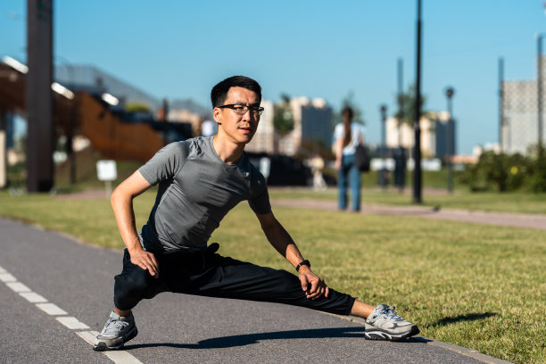 亚洲成年男子在公园慢跑前做热身运动。图片下载