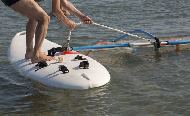 为风帆冲浪做准备。冲浪者的手拉着绳子来提升帆。图片下载