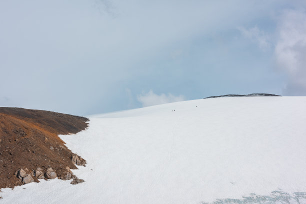 风景秀丽的高山景观与小人物在高高的雪山阳光下在蓝天白云下。令人惊叹的山景与小游客在阳光明媚的大雪山在多变的天气。图片下载