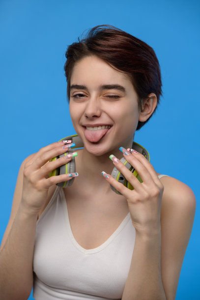 年轻漂亮的黑发姑娘，脖子上戴着耳机，吐着舌头胡闹图片下载