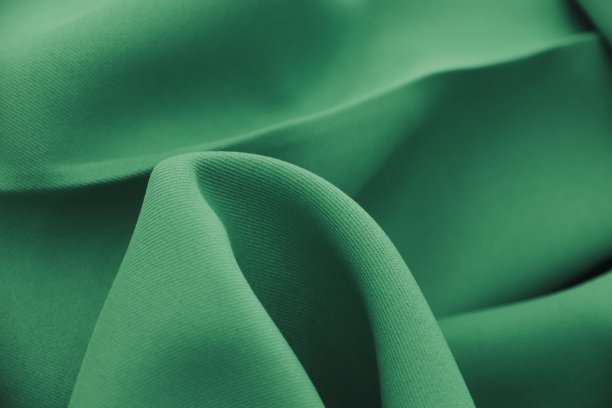 绿色布料纹理背景特写。绿色帆布背景，丝绸缎面织物背景图片下载