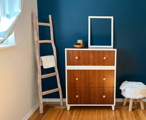 阁楼风格的乡村客厅，一个有口音的梳妆台对着一扇窗户和一个装饰性梯子的午夜蓝色的墙图片下载