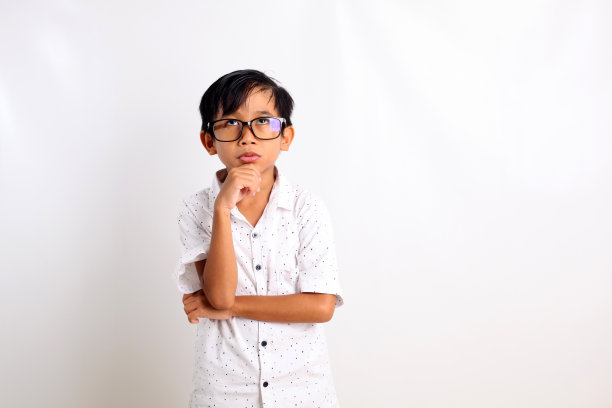深思熟虑的亚洲男孩站着向上看。孤立的白色背景与复制空间图片下载
