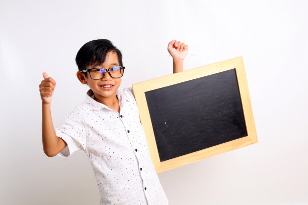 快乐的亚洲男生站在黑板前竖起大拇指。孤立在白色图片下载