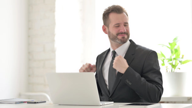 年轻的商人在办公室用笔记本电脑跳舞图片下载