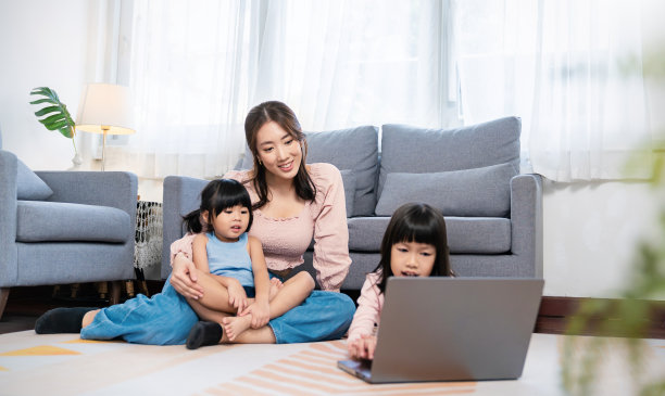 特写亚洲家庭的母女坐在餐桌上双手使用电脑，一起直播zoom在线交流，居家隔离呆在一起连接，教育休闲的人们。图片下载