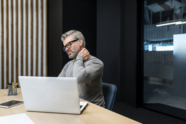 在写字楼里工作的资深成熟商人，头发花白的男人用手按摩着脖子，疲惫不堪，老板的脖子和背疼得厉害图片下载