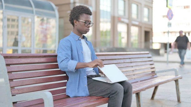 年轻的非洲男子关闭笔记本电脑后离开长凳图片下载