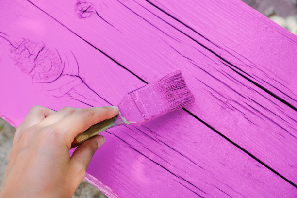 一个人用手中的画笔把木头表面涂成粉红色图片下载