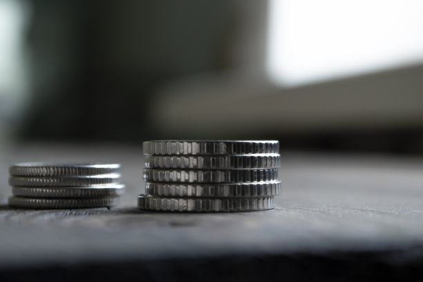 木桌上有两叠硬币。币方微距射击。钱在桌子上。铁鳗堆在一起。图片下载