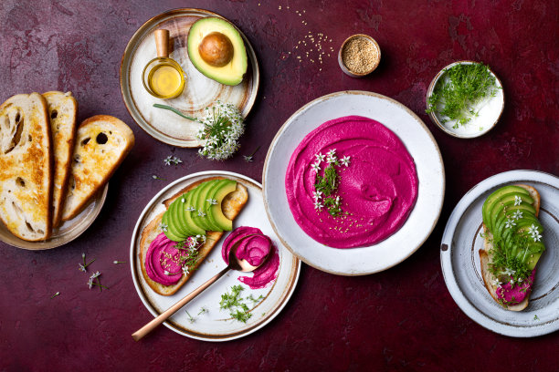 牛油果吐司配粉色甜菜鹰嘴豆泥或蘸上可食用的洋葱花和微绿色蔬菜。以植物为基础的健康开胃菜，素食，素食小吃图片下载