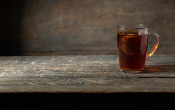 一杯茶，木制背景上有一个香包。图片下载