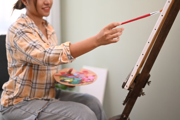 快乐的年轻女子用水彩画在舒适的家里。艺术、创意爱好和休闲活动理念。图片下载