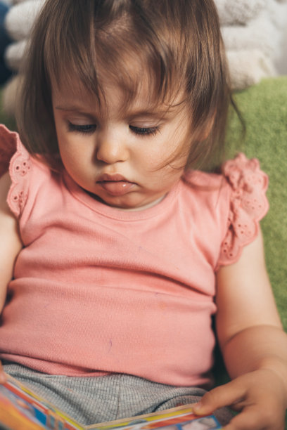 一个小女孩坐在沙发上检查一本书的特写。孩子的发展。孩子的教育。图片下载