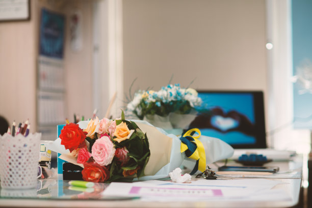 老师的桌子上放着一束花，上面系着黄蓝相间的丝带图片下载