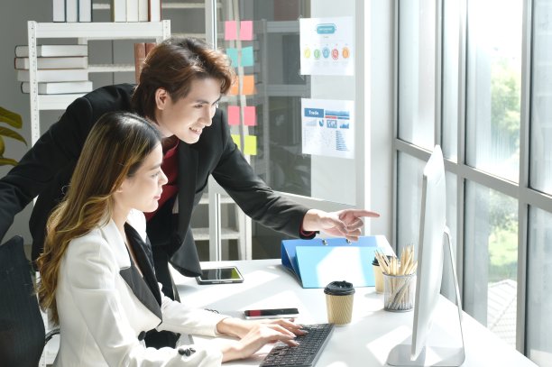 亚洲商人男女看着笔记本电脑屏幕讨论和工作图片下载