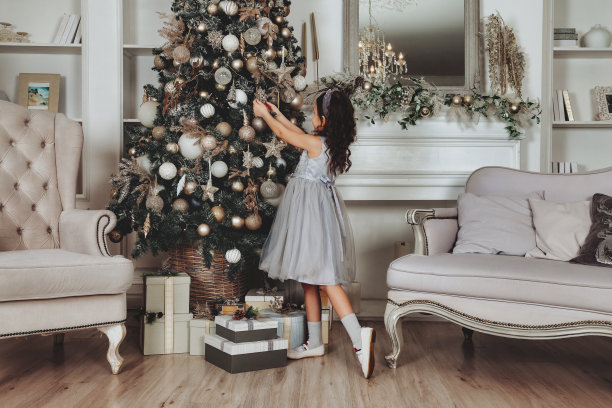 温馨的家，小女孩在喜庆的客厅里装饰玩具圣诞树。家庭氛围时刻圣诞快乐，新年快乐的概念。复制文本空间图片下载