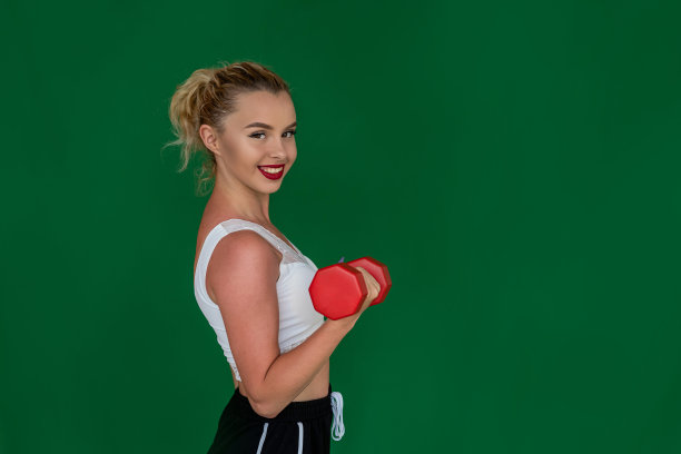 健美身材的美女在训练中展示她更喜欢哪个哑铃。图片下载