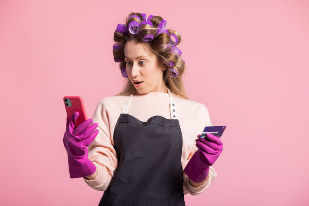 年轻美丽的金发女子在手机上浏览电子产品，吸尘器，拖把，通过手机应用程序商店在线购买清洁配件，用卡支付送货到家图片下载